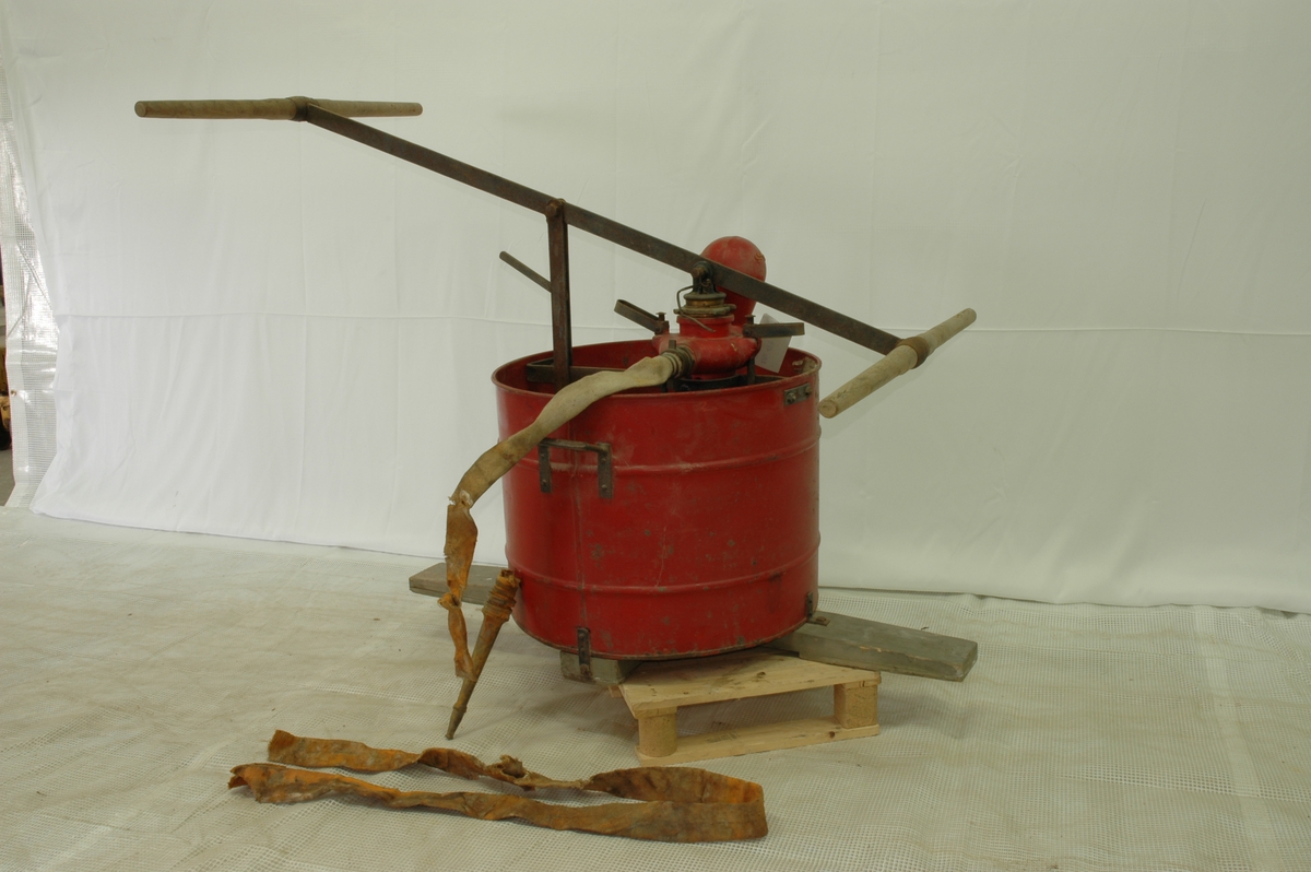 Rød vanntønne med pumpe og slange for brannslukking