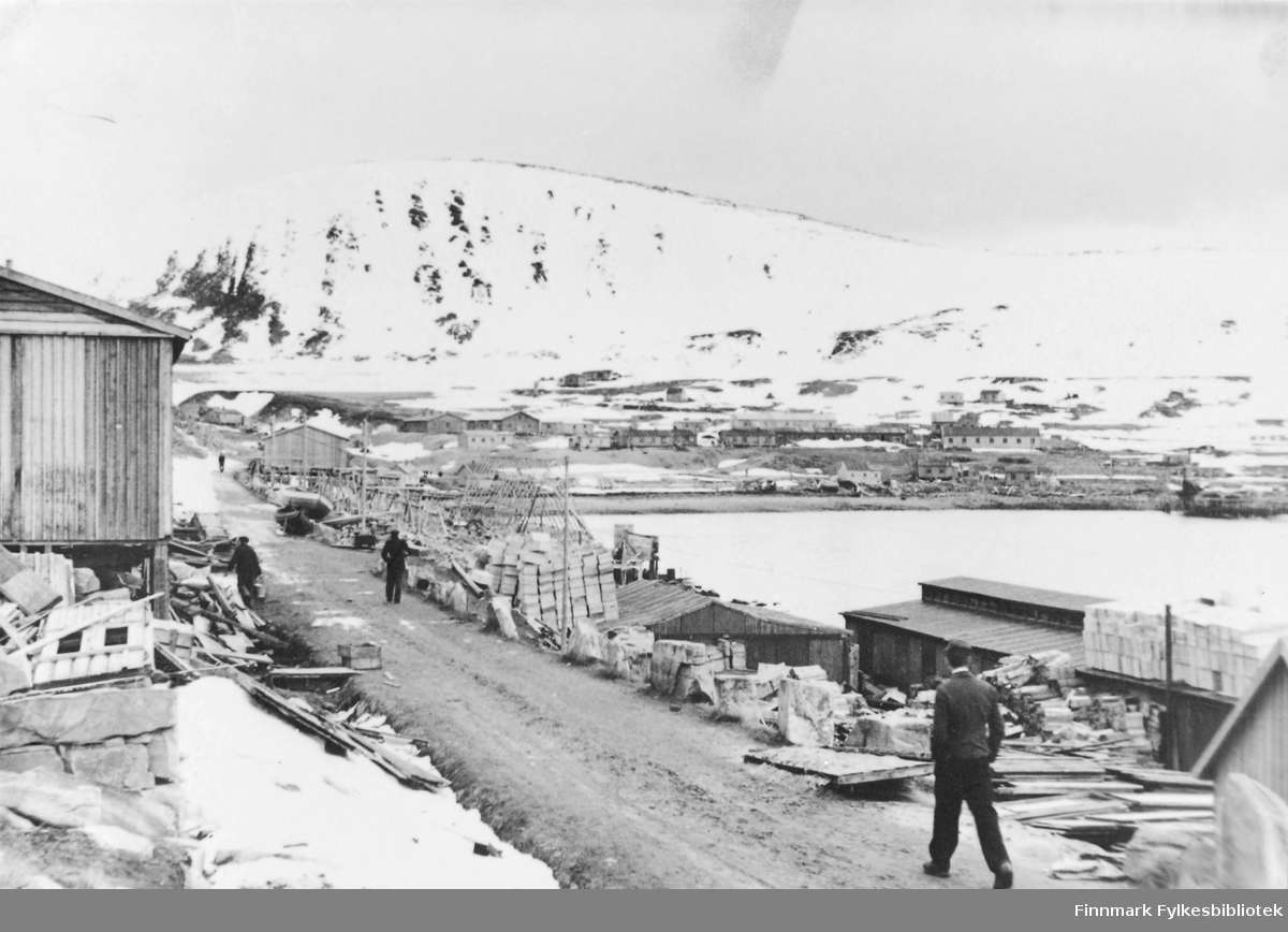 Oversikt og over Kjøllefjord, mai 1946. Fra en vei. Materialer ogbåter i veikanten. I bakgrunnen ser vi boligbrakker.