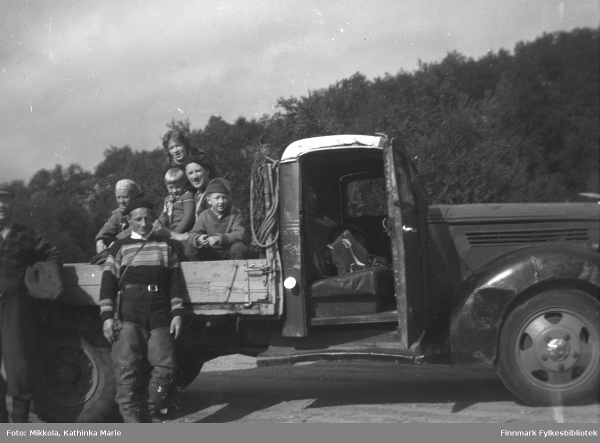 Familien Mikkola klar til tur med Storm Mikkolas Ford V8lastebil (årsmodell 1938-39). På lasteplanet Synnøve og Per Sivle Olsen med barna Grete Lill (stående bak), Liss-Marion og Tore. Stående fra venstre Aksel Konrad Mikkola og Halvor Lindseth. Bildet er tatt på Mikkelsnes.