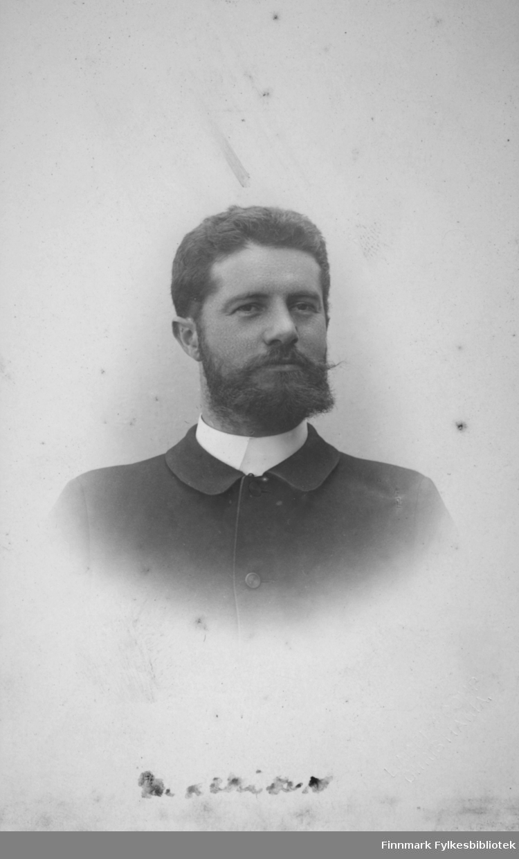 Portrett av en mann iført mørk dressjakke. I halsen ses litt av den hvite kragen.