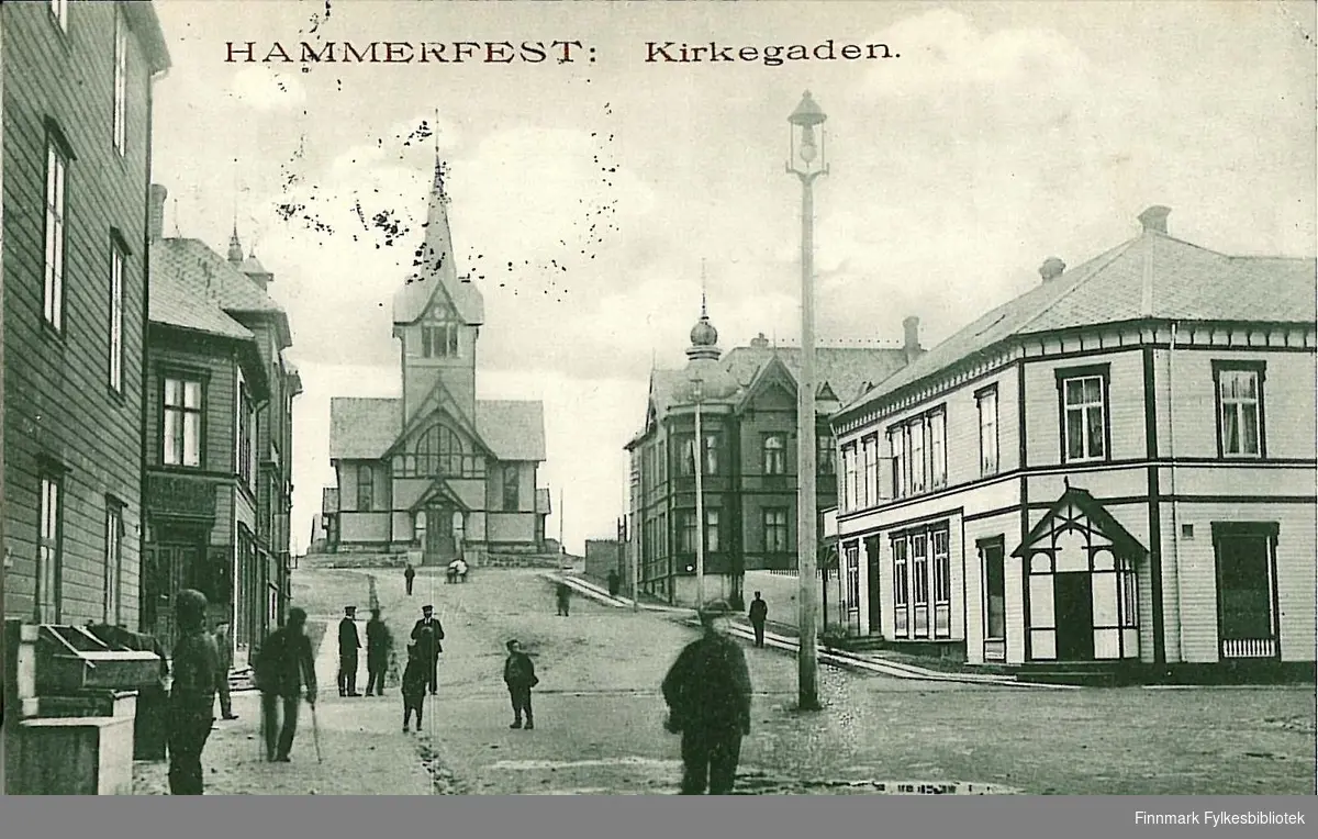 Postkort med motiv fra Hammerfest sentrum. Kortet er en jule- og nyttårshilsen til Arthur og Kirsten Buck på Hasvik. Kortet er sendt fra Hammerfest i 1906.