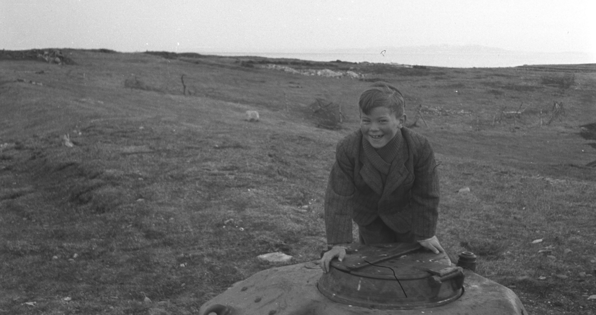 Øystein Hauge fotografert på Vadsøya like etter andre verdenskrig. Han lener seg mot et lokk som er et tårn fra en stridsvogn (stridvogntårnet er APX-R tårn til Renault R35/R40 og Hotchkiss H35/H39).