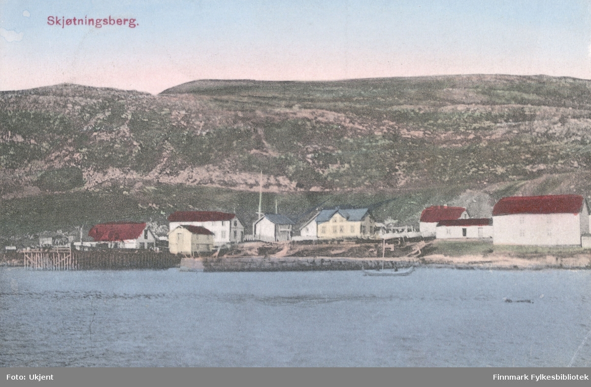 Et postkort med Skjøtningsberg som motiv. På bildet kan man se en havn med kai, båter, en mollo(?) og bygninger. I bakgrunnen kan man se fjell.