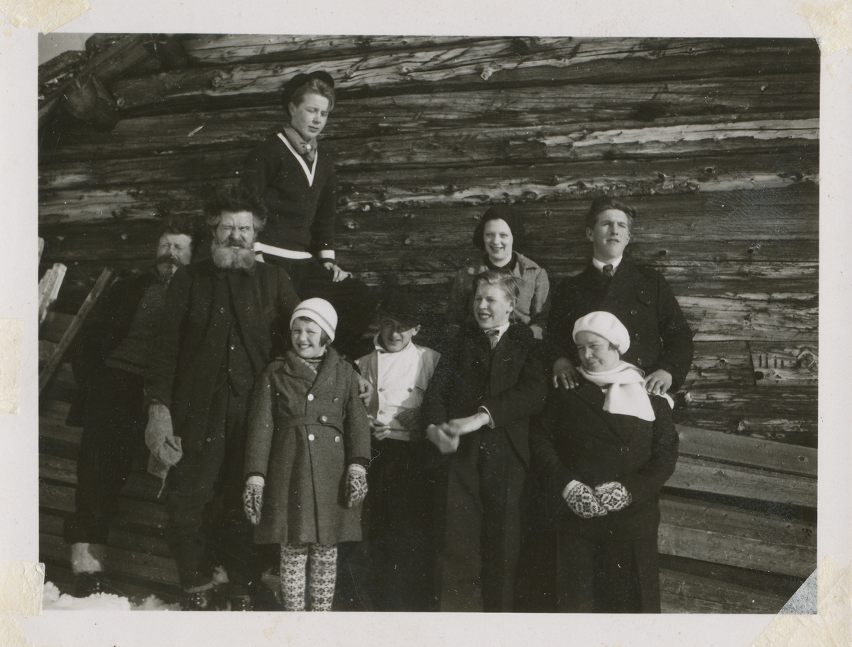 En gruppe mennesker foran en tømmervegg som skal være Ingvald Skjeldrup med venner.