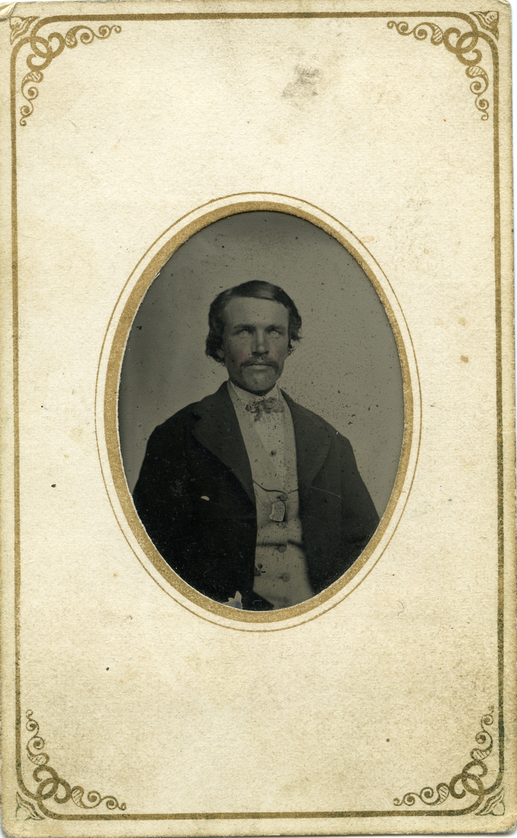 Portrett av mann foran lerret. Mannen er iført dress med vest og tørkle i halsen.