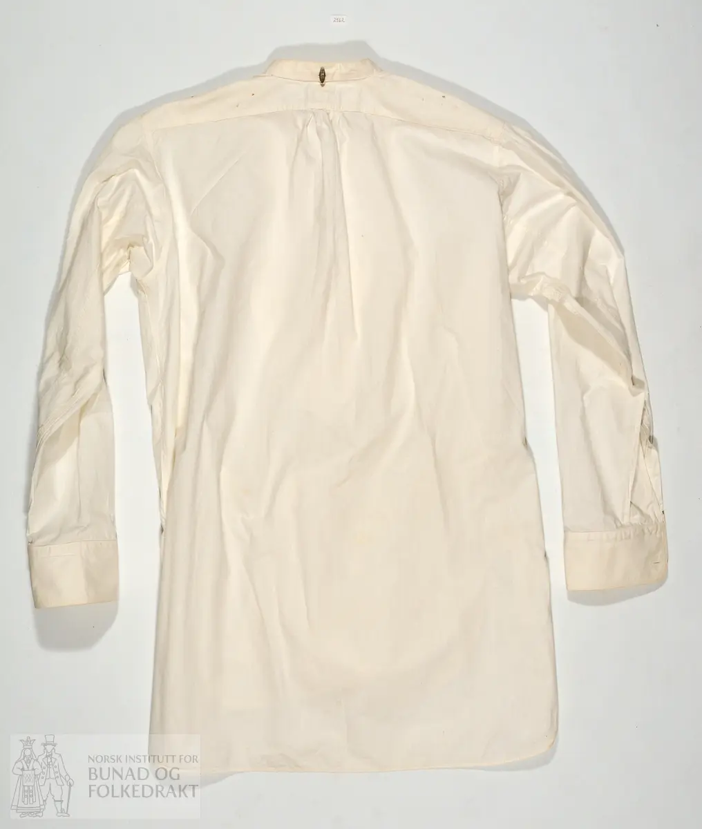 Skjorte kjøpt på butikk, med merkelapp i nakken AL 1898. Stiva skjortebryst. Maskinsydd. 85cm midt bak og ned.