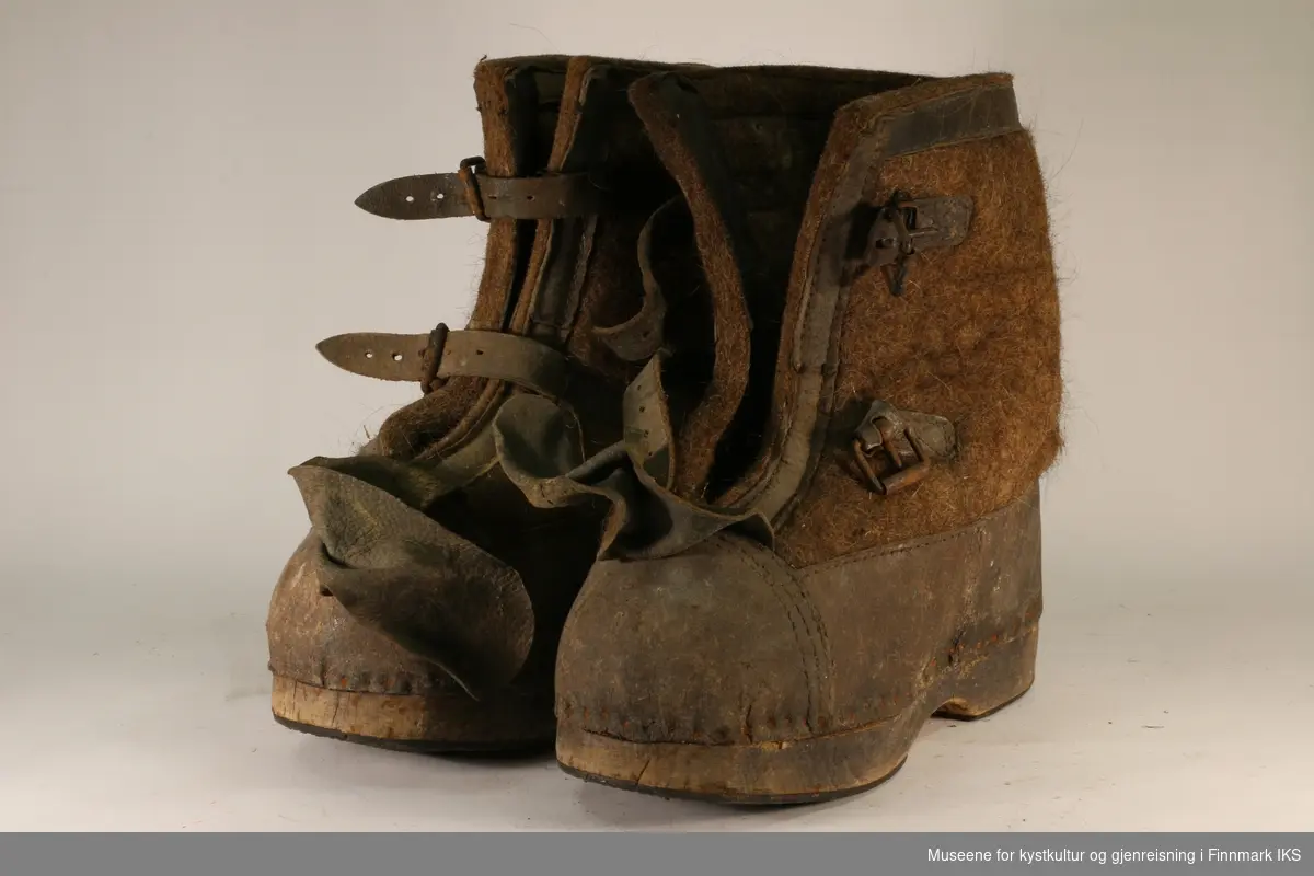 Et par filtstøvler med trebunner og lukking med to remmer. 

Tyske militærstøvler fra krigens dager. Senere brukt under arbeid på tørrfisklageret på Floerbruket.

Påsydd merkelapp inni skoen; teksten uleselig.