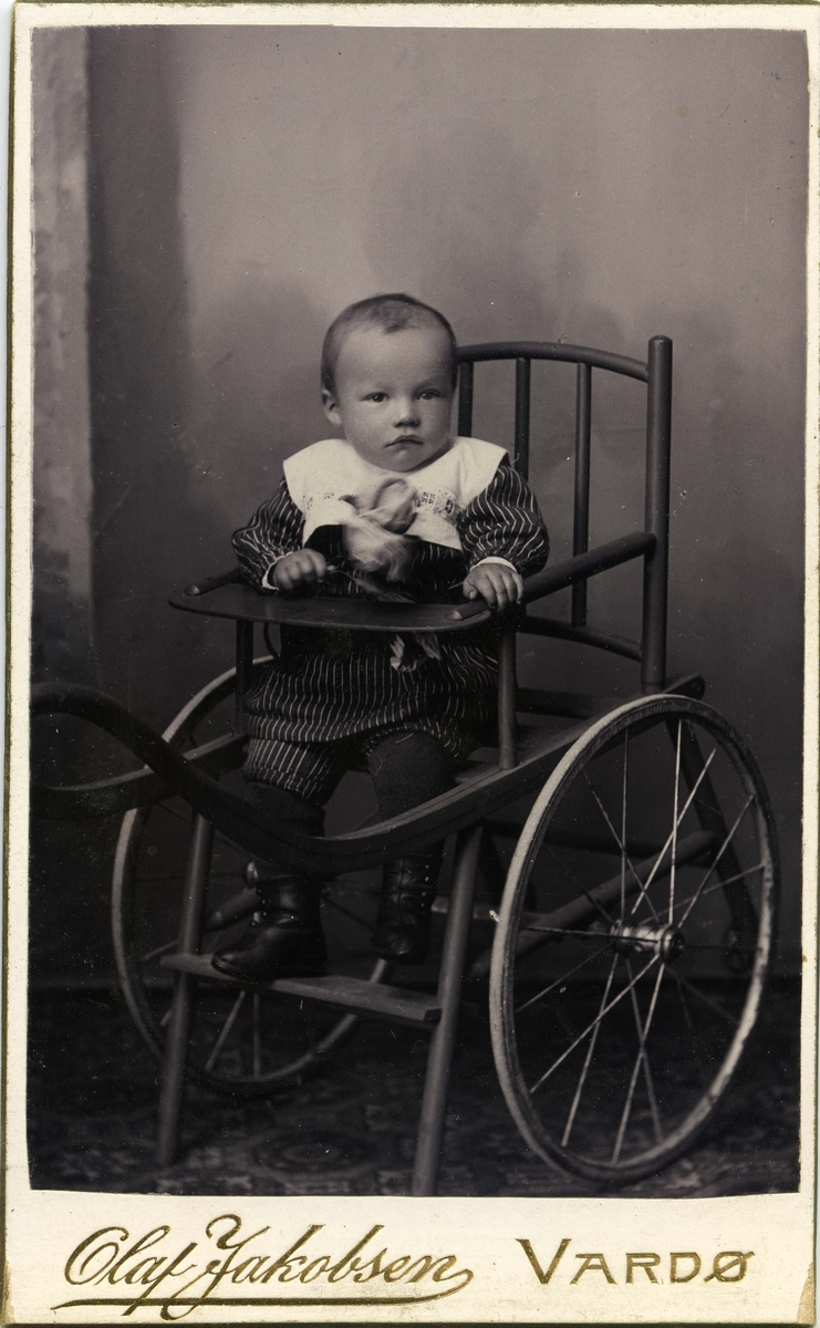 En liten gutt sitter i en stol med hjul.
