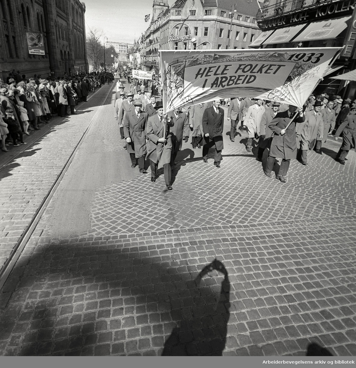 1. mai 1962 i Oslo.Demonstrasjonstoget i Karl Johans gate.Parole: 1933 Hele folket i arbeid.Parole: 1936 Lov om alderstrygd.