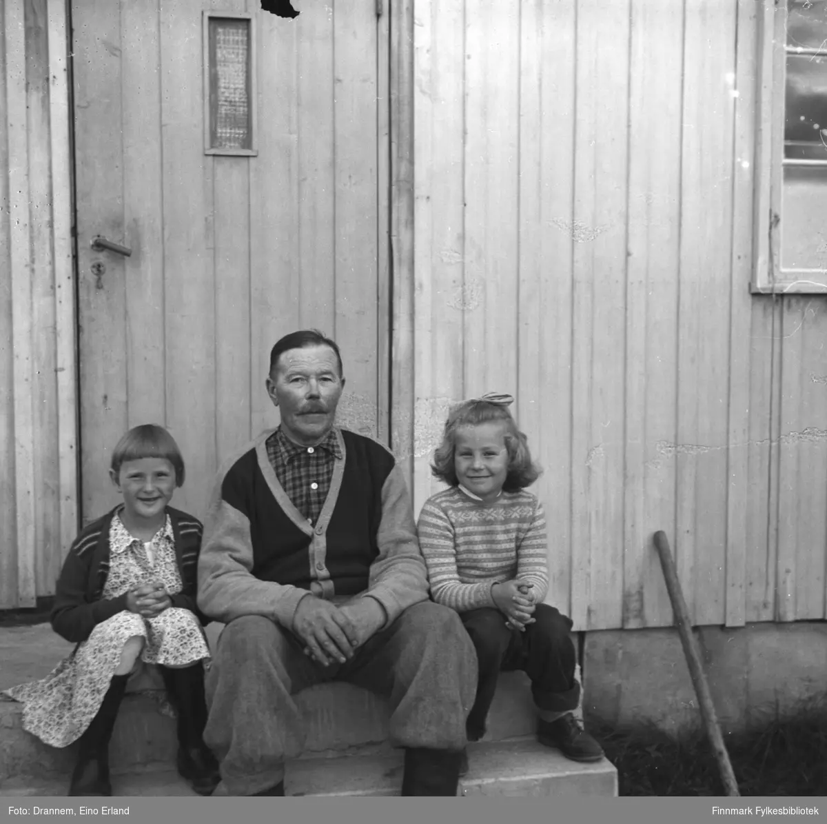 Alfred Karikoski, Turid Lillian og en gjest (ei jente til venstre) sitter på trappen utenfor huset i Steinnes i Neiden