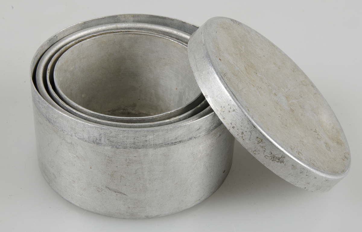Liten metallburk innehållande metalldelar som tillsammans bildar en mugg.