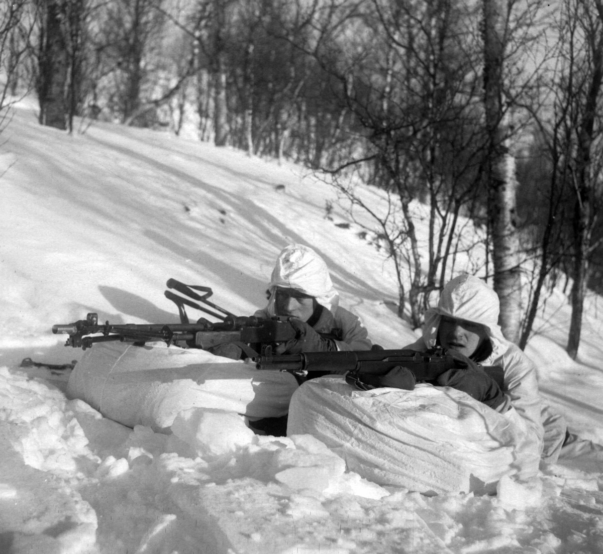 To soldater i stilling under en vinterøvelse.