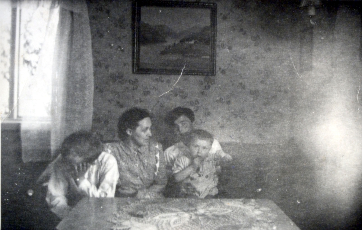 Fire personer fotografert i en stue, muligens i Kvalsund kommune før evakueringa. Personene er ukjent.