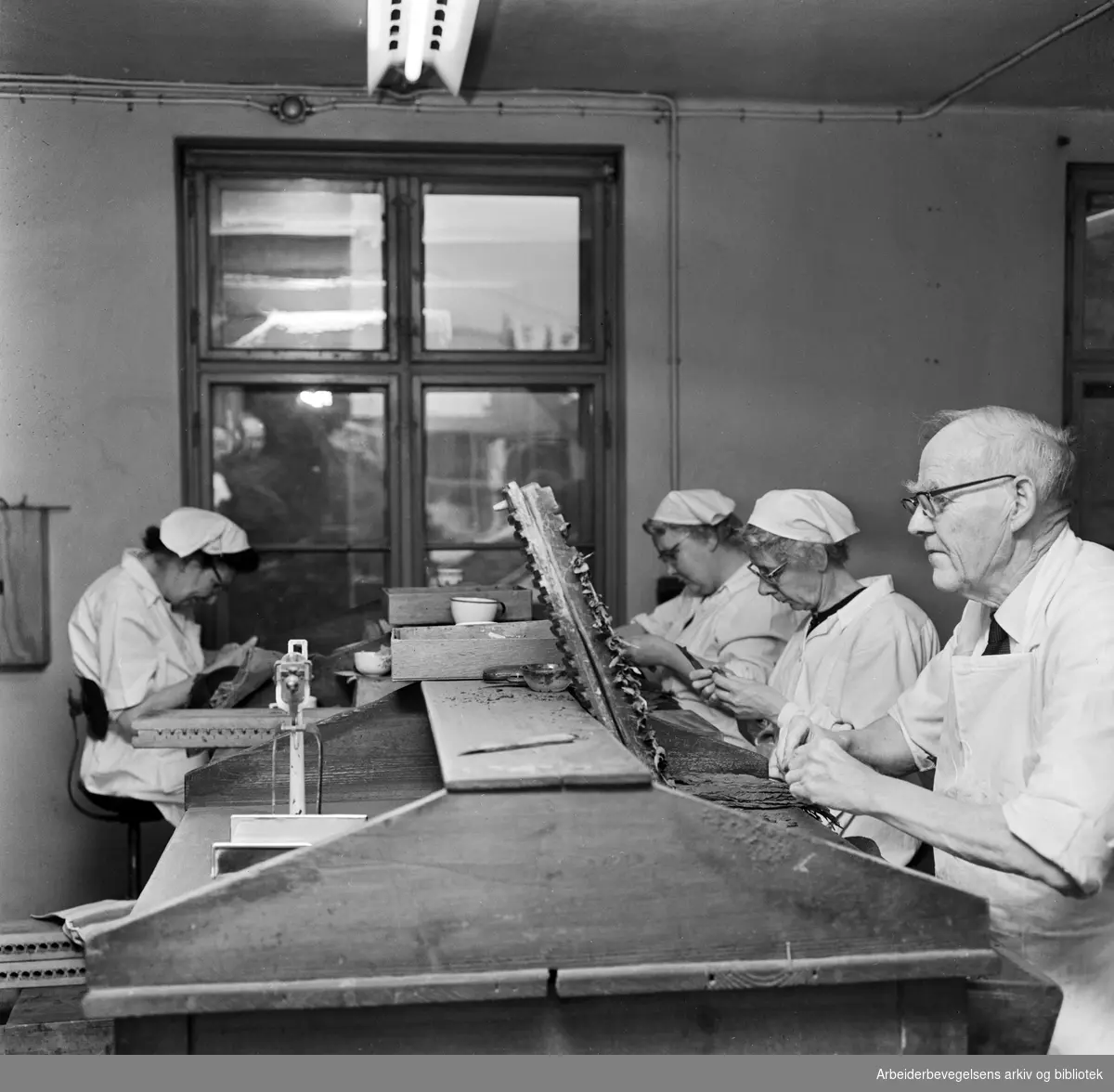 Sigarmakere ved Johannes N. Withs Tobakfabriker, tilhørende J. L. Tiedemanns Tobaksfabrikk. Fra h. Aksel Kristoffersen, Ingrid Hansen, Olga Aadim og Margit Steen. Desember 1961.