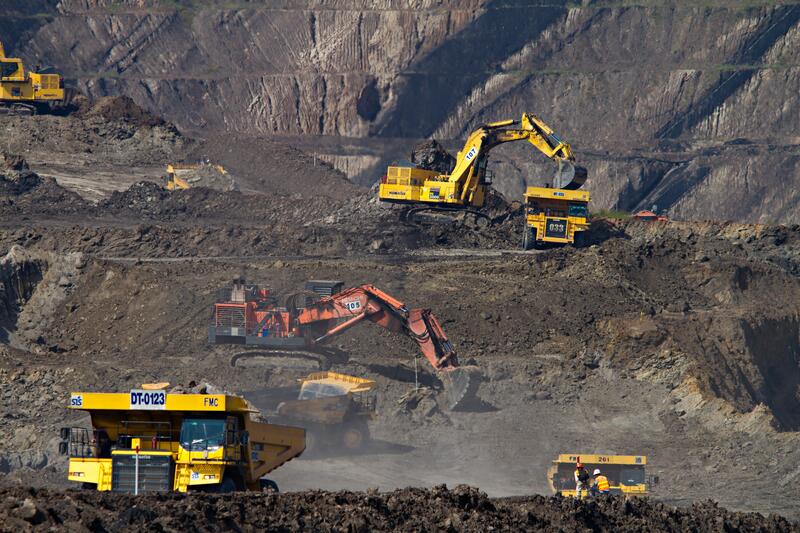 Bildet viser gruvedrift over jord, med mange lastebiler og kranbiler