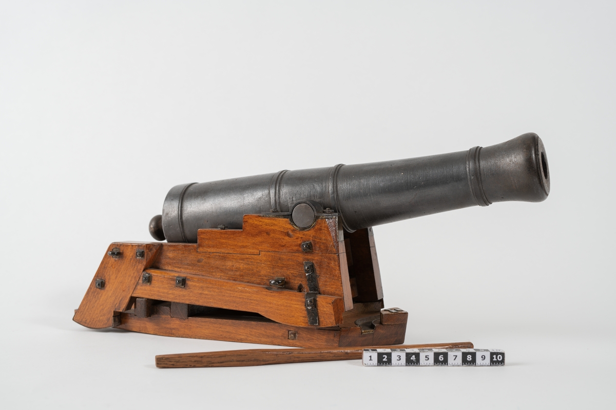 Kanonmodell: styckelåda, modell av trä, beslagen, med kanon av järn, 24-pundig, kapten Malmstens modell. Tillbehör: 1 st brok.