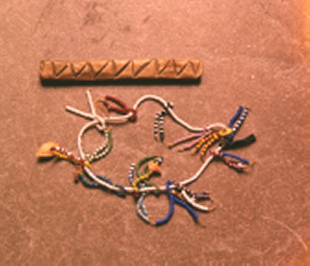 Pärlbrev, kärleksbrev från Buthelezi-stammen i Zululand (nuvarande provins KwaZula-Natal), Sydafrika. Halsband utgörs av vita pärlor och pärlraderna är olikfärgade. Färgerna på pärlorna, den ordning de har eller de mönster som uppstår har olika betydelser. Ett frö, en bit av en pinne, ett skal och en metallpärla är trädda på hängena, även dessa föremål har olika betydelser. En kedjelänk som syns på fotot, har förkommit. Mottagaren tolkar brevets budskap och kan sedan bära det med sig, vanligen som ett smycke kring halsen.