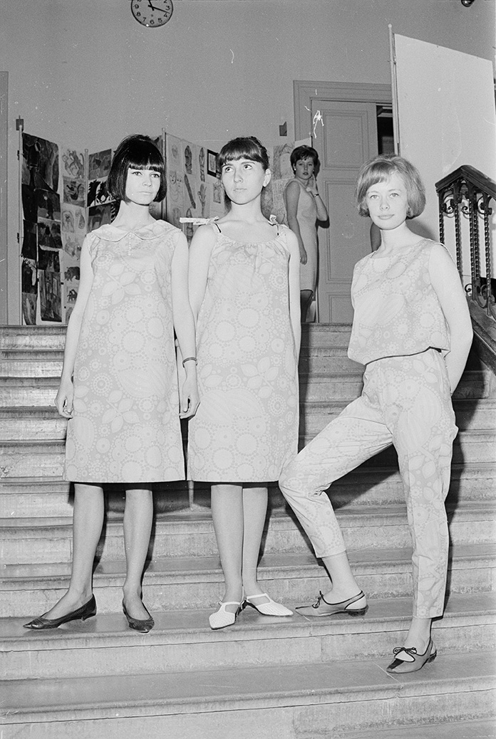 Modevisning. Tre tjejer står i trappan i mönstrade dräkter.