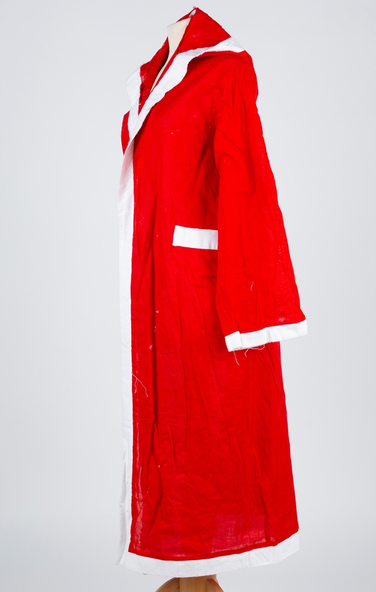 Julenissedrakt i bomull og syntetisk materiale, lang rød frakk med hette, kantet med hvitt stoff, med tilhørende hjemmelaget hvitt skjegg. Snor til belte. Voksen størrelse.