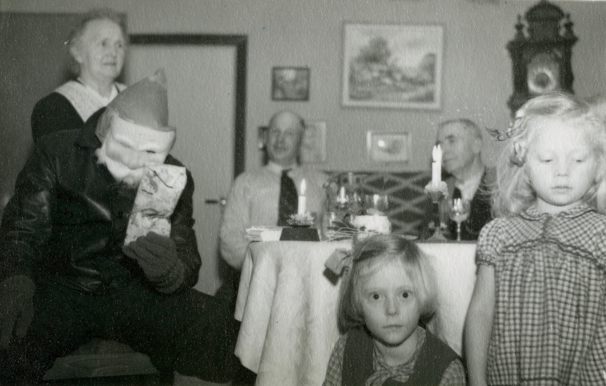 Julafton hemma hos familjen Pettersson på Gamlehagsvägen 17, Torrekulla år 1951. Från vänster ses Nora Krantz (1879 - 1955), Jultomten, Karl Holmberg och Carl Krantz (1880 - 1956). I förgrunden ses systrarna Karin (född 1947) och Eva (född 1944) Pettersson, barnbarn till Nora och Carl.