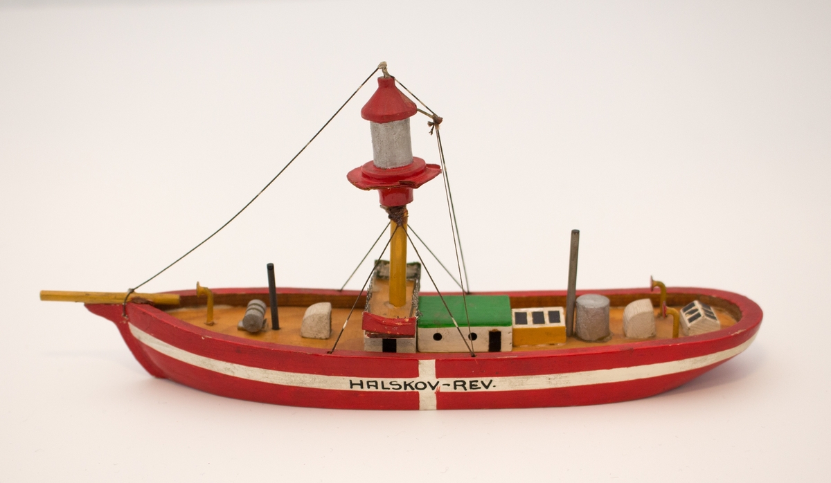 Liten suvenirmodell/miniatyrmodell av fyrskipet HALSKOV RED med fyrlykt i masten. Skrog flat i bunn ved vannlinjen.