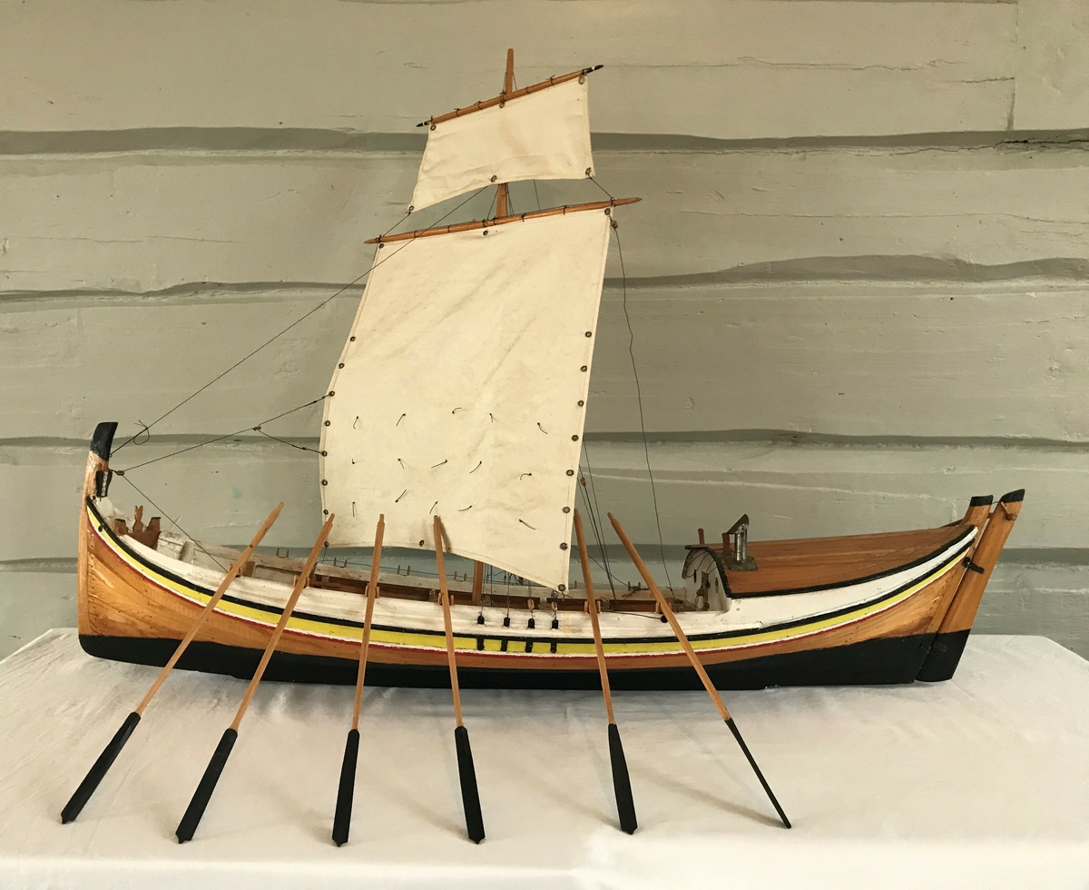 Båtmodell av en fembøring med høtt/klepp, øsekar, båtshakk og 13 årer
