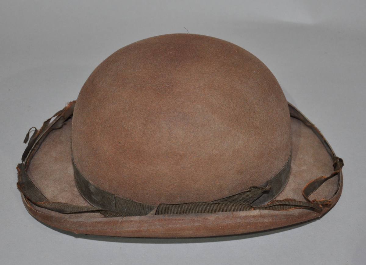Rund hatt av skinn. Hatten har lys brun farge, og brem med svungen form.