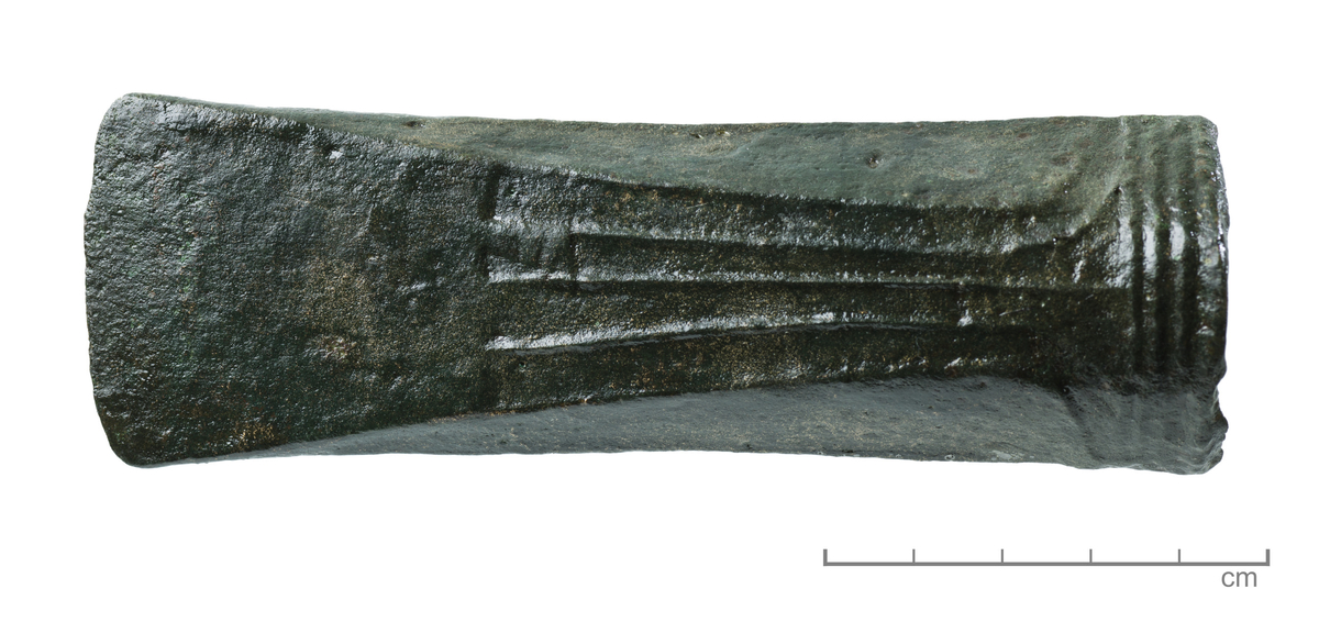 "4572. Celt av bronse nærmest som Minnen fig. 993, 12,6 cm. l., bredde i eggen 4,2 cm. Fra bronsealderens 3. periode." 