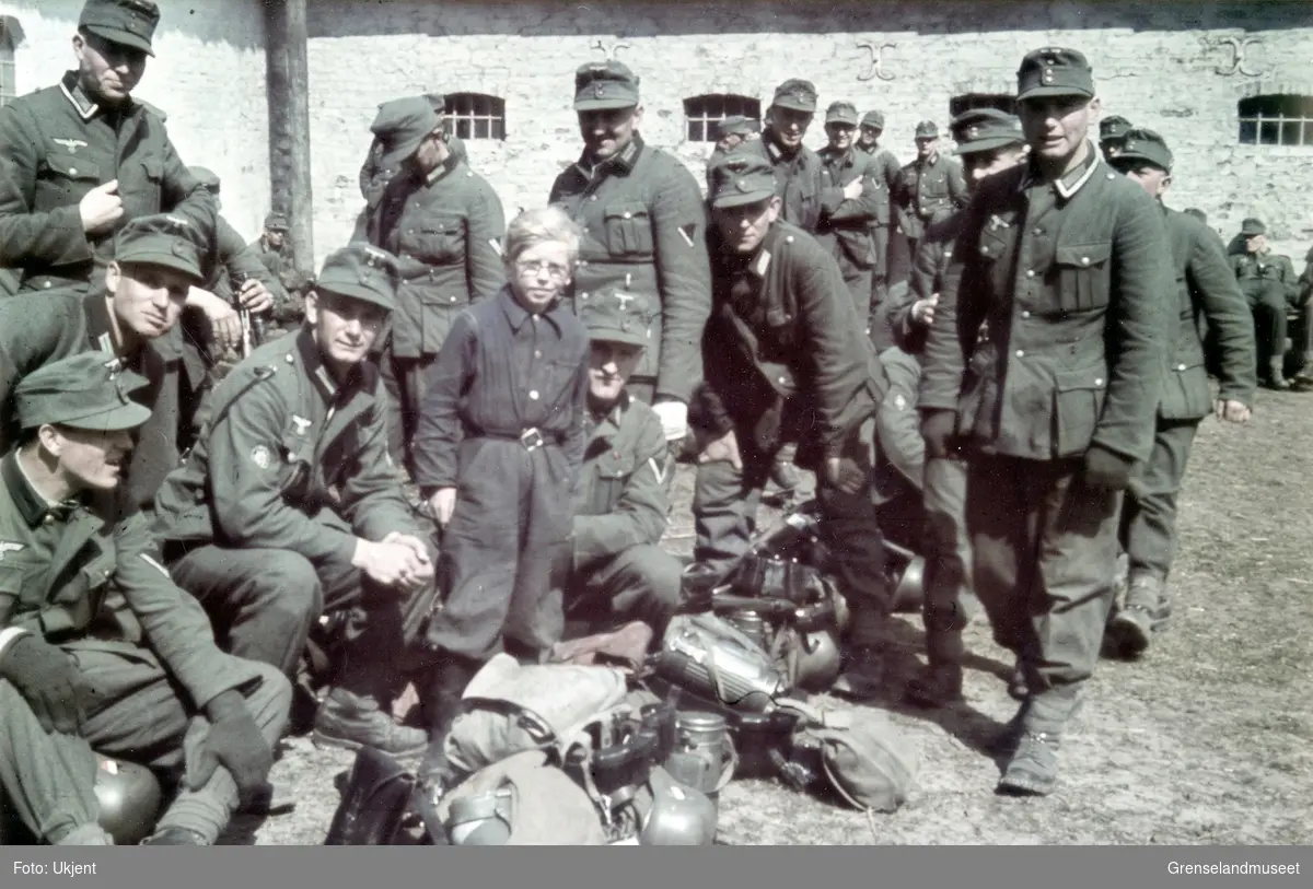 En gutt står sammen med en gruppe soldater. 