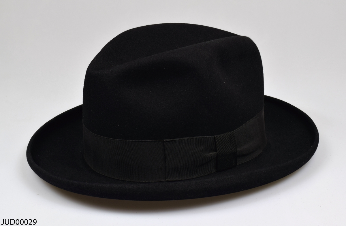 Hatt liggandes i sin originalkartong. Hatten är tillverkad av svart filt, med brunt läder och beige siden inuti.
