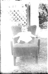 En liten unge sitter i en stol.