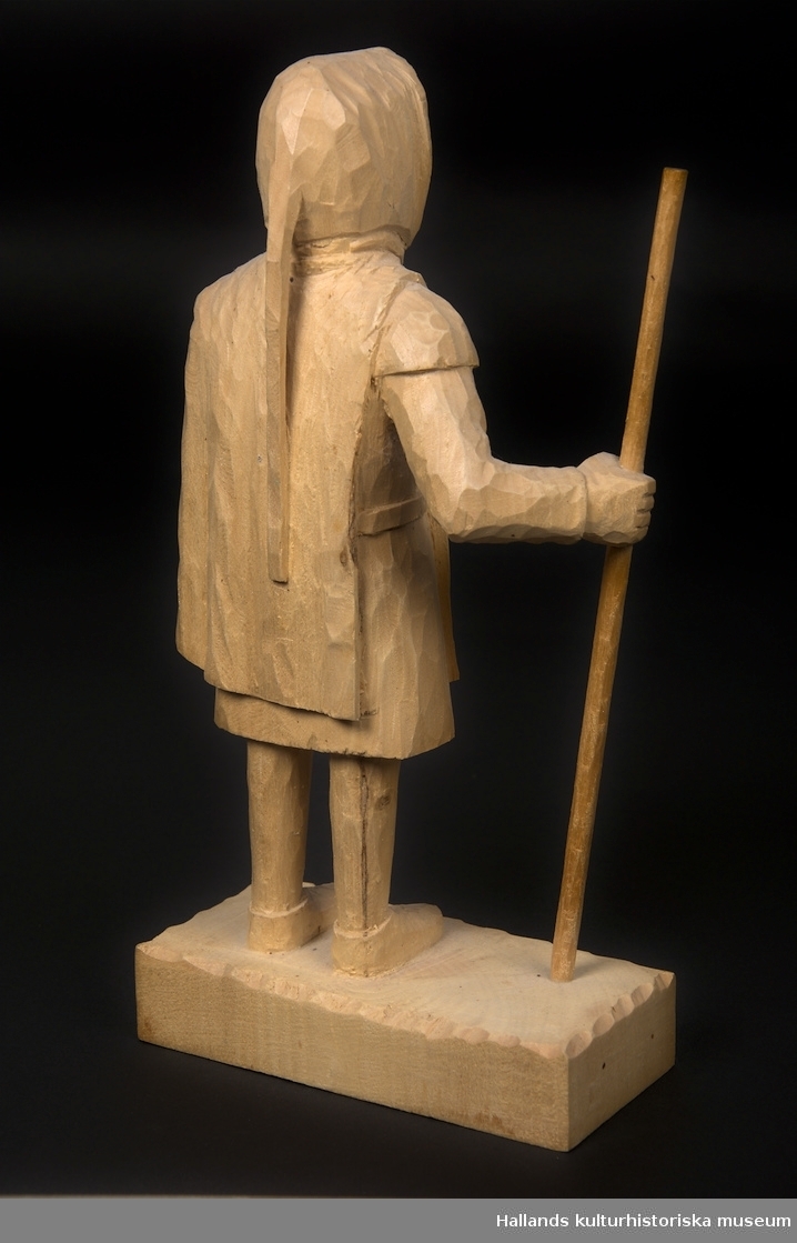 Skulptur av lindträ föreställande Bockstensmannen. Behandlad med klarlack. Signerad "GG" med brännmärkningspenna undertill.
Skulpturen är, utöver vandringsstaven, snidad i ett trästycke.