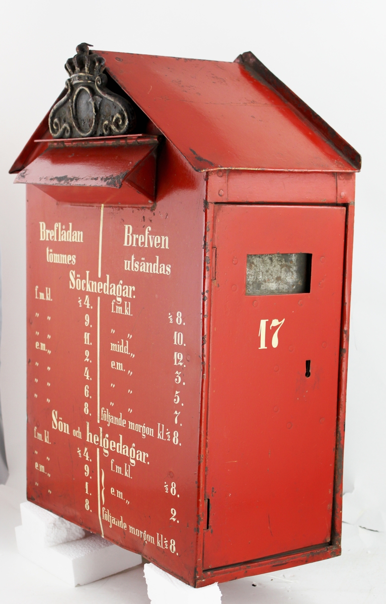 Brevlåda med sadelformat tak, tömning från sidan (höger) genom att öppna en låsbar lucka. Brevlådan har ett gjutet postemblem ovanför inläggsluckan. Brevlådetypen är en tysk uppfinning som det svenska Postverket införde 1856 på Södermalm i Stockholm. Brevlådan var en så kallad dubbel brevlåda; inne i brevlådan fanns nämnligen ytterligare en låst låda av bleckplåt. Vid tömningen drogs innerlådan ut och ersattes med en tom. Den låsta innerlådan transporterades sedan till postkontoret för tömning. Brevlådan har tömningstider och utsändningstider angivna på framsidan.