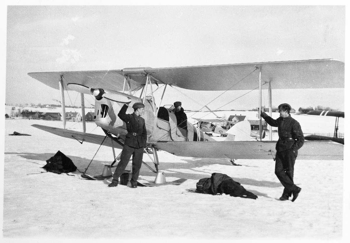 Tiger Moth tilhørende Hærens Flyvåpen avbildet på Kjeller flyplass året 1939. Personene på bildet er flysoldatene Høgetveirt, Eek og Graver. Noen fornavn foreligger ikke.