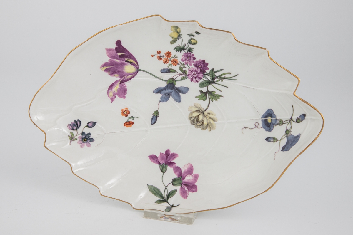 Ovalt bladformet fat med bladnerver i relieff, polykrom blomsterdekor i overglasur og forgylte kanter.