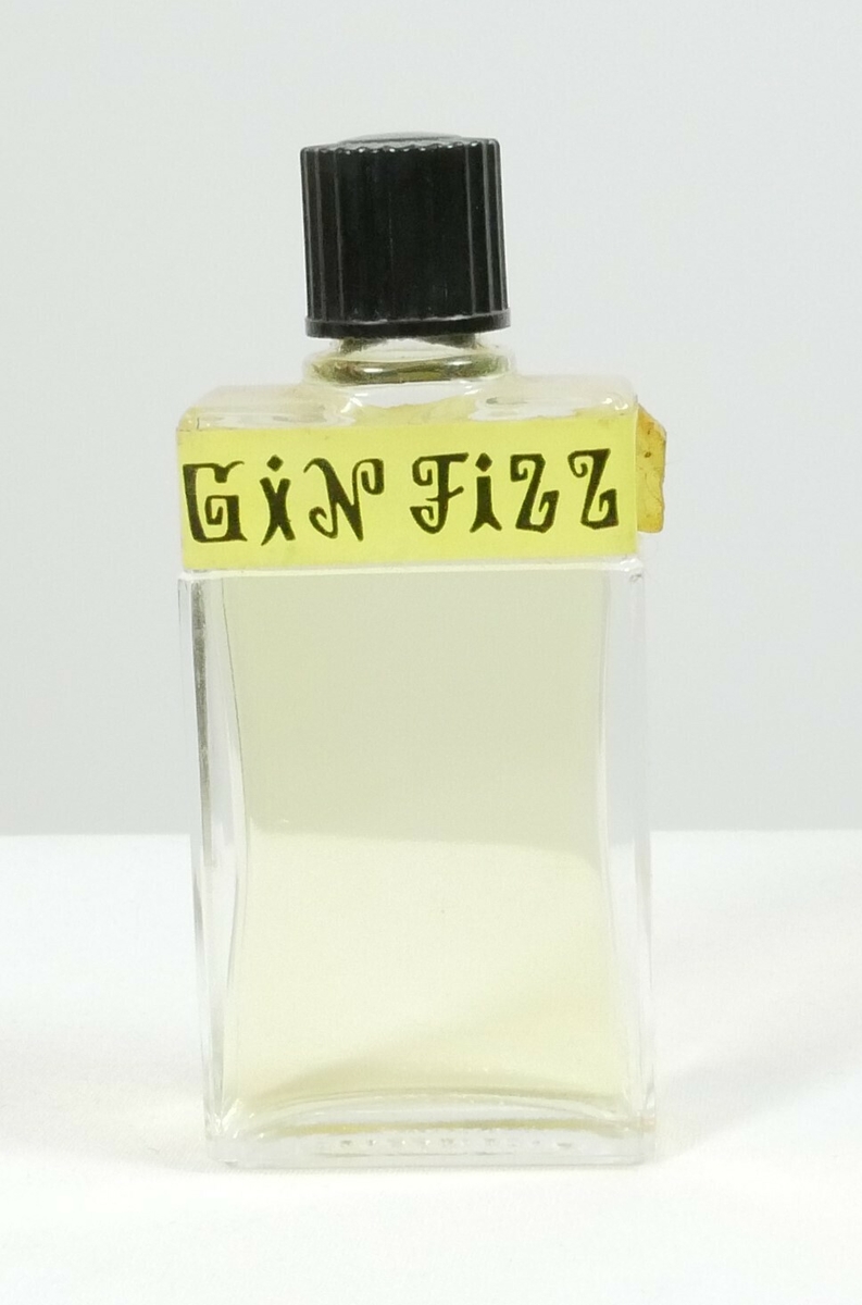 Rektangulær klar glassflaske med en svart rund plastkork. Øverst er det en påklistret gul etikett. Flasken inneholder en gul væske. 

Påskrift, etikett: 
GIN FIZZ // 90 // LUBIN // PARIS FRANCE // LUBIN
