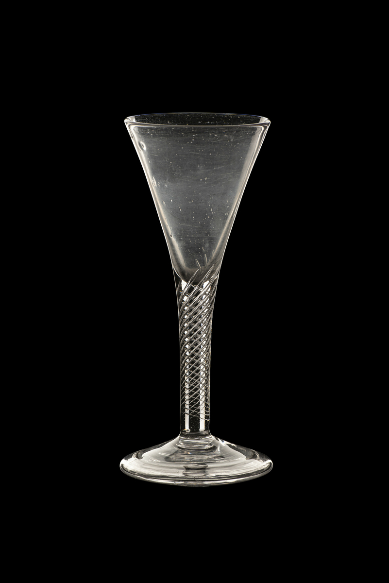 Vinglass, modell "Viin Glas Slange Kelchen Chrÿstal". Klart, tilnærmet fargeløst glass. Trompetformet stett og klokke, med luftspiraler i stetten. Rund, lett hvelvet fot med ombøyet fotkant.