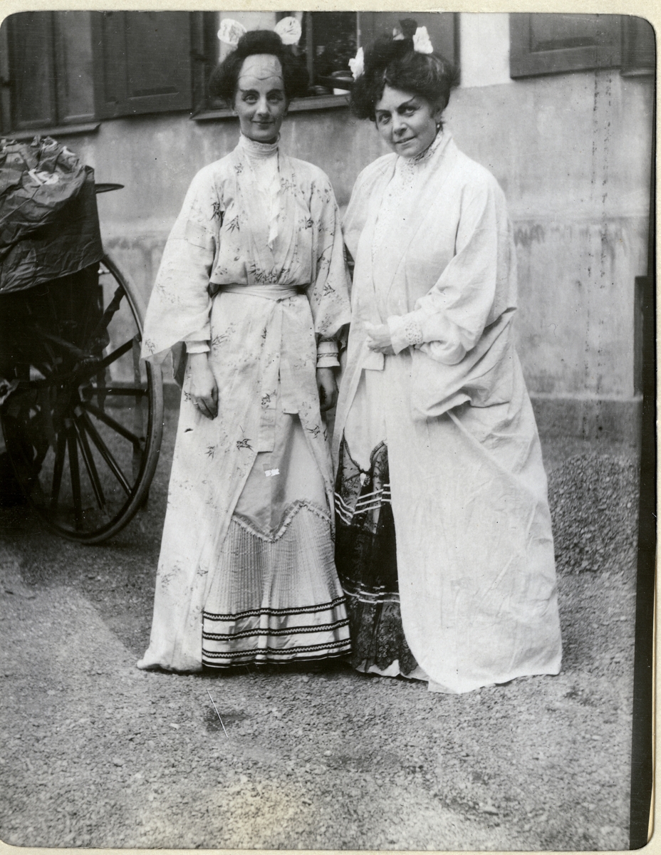 Nini Egeberg og hennes mor, Mathilde Wedel Jarlsberg, i utkledning på Barnehjelpsdagen. Til venstre hestekjøretøyet som de skal bruke i forbindelse med opptoget. Fotografert 7. juni 1906.