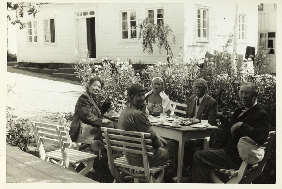 Lilly Egeberg, frk. Ruud, Mimi Grieg Halvorsen, Viktor Plathe og Westye Egeberg rundt et hagebord i Brekkestø sommeren 1953.