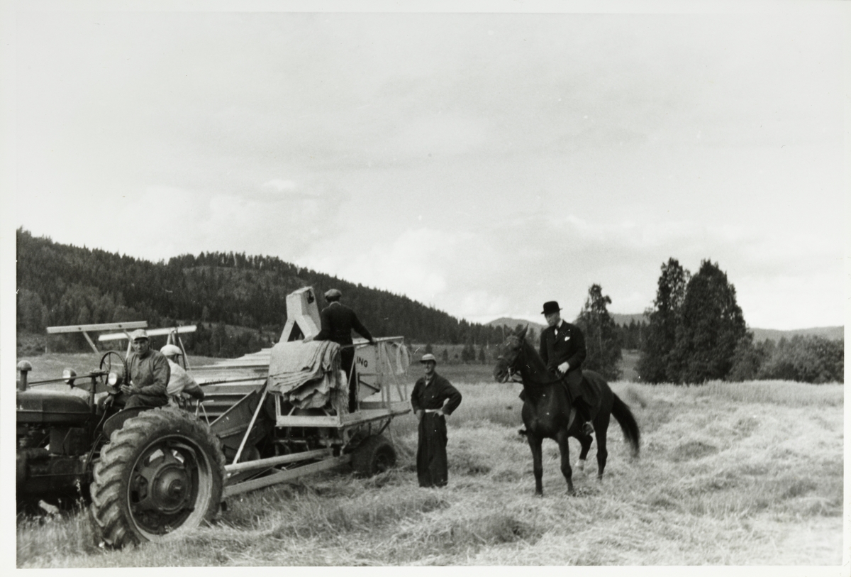 Westye Parr Egeberg på sin røde ridehest "Flickan" inspiserer innhøstingen med skurtresker på Bogstad gård. Ved skurtreskeren står agronom Hagelund. Fotografert 1954.