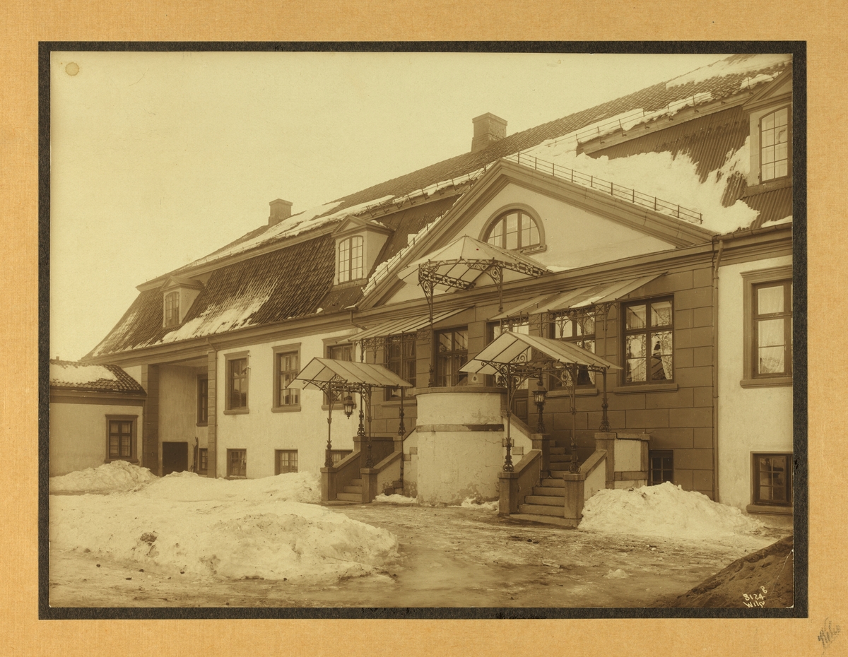 Eksteriør fra Bogstad gårds hovedbygning før ombygningen i 1914. Baldakin over inngang og trappene. Gårdsrommet dekket av snø.
Trappen ble bygget i 1854 men ble revet under ombygningen for å gi plass til et tilbygg og en trapp som førte til andre etasje på innsiden av huset.