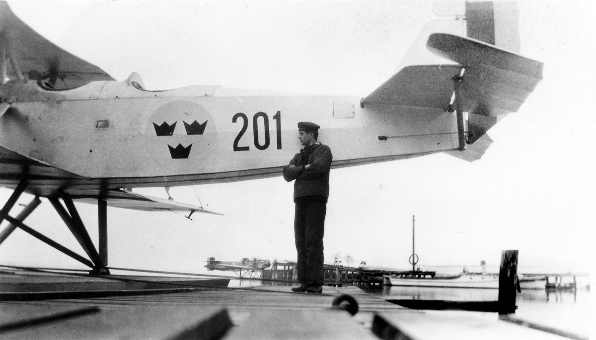 En man ur marinen står på en brygga vid sjöflygplan Sk 4, Heinkel HD 24 nummer 201. 1930-tal.