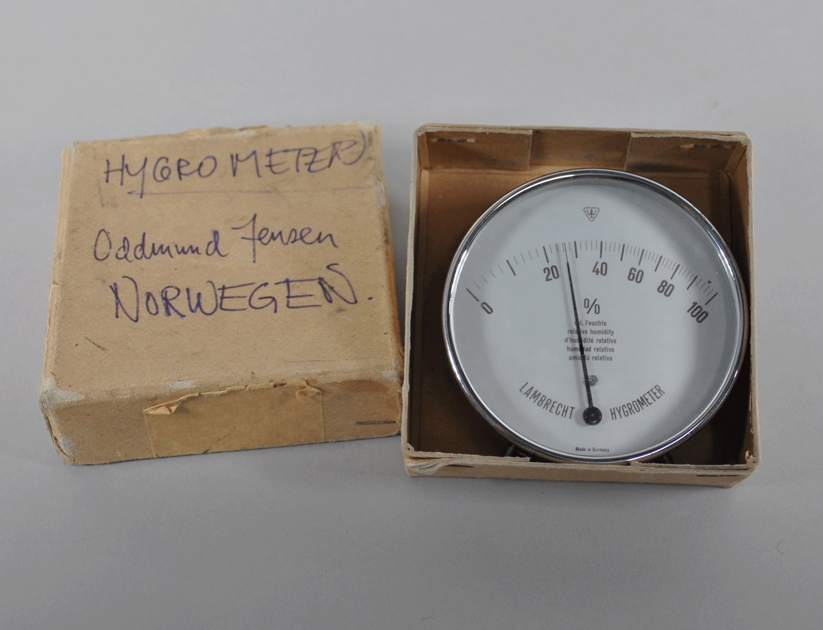 Rundt hygrometer med to visere, som måler fuktighet. Hygrometeret ligger i original emballasje.