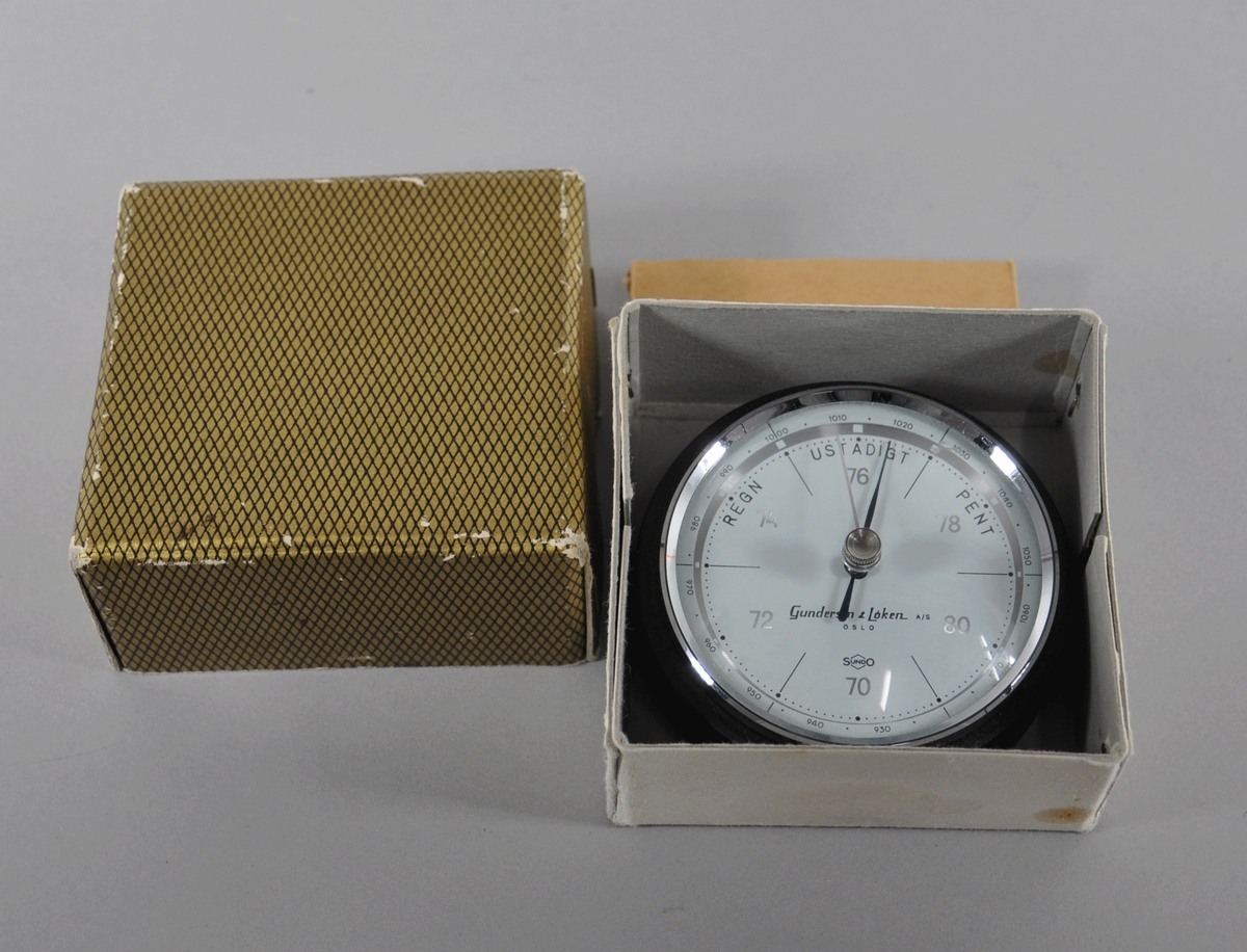 Rundt hygrometer med to visere, som måler fuktighet. Hygrometeret ligger i original emballasje.