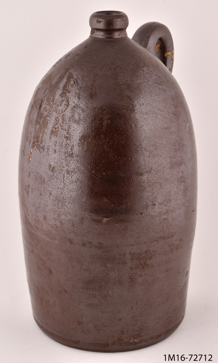 Krus av stengods, brunt, cylinderformat med avsmalnande kort hals, ett öra. Märkt: L Helsingborg 2.