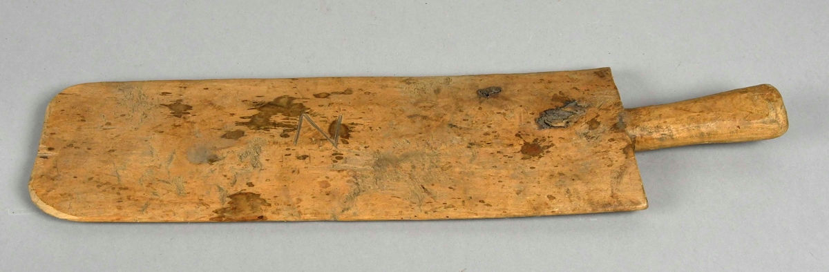 Skakekniv av tre, laget av ett trestykke med håndtak og knivblad. Bladet er ca 1 cm tykt på midten