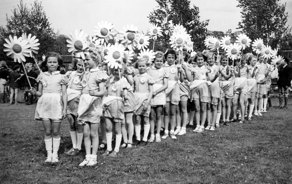 Barnens dag 1951. En grupp flickor håller konstgjorda blommor och står uppställda inför paraden.