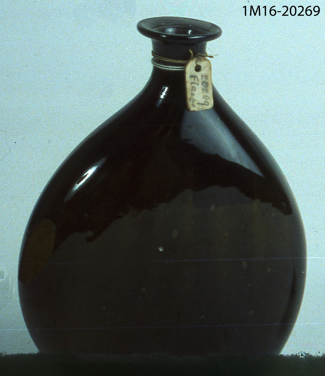 Flaska av mörkbrunt glas, platt.