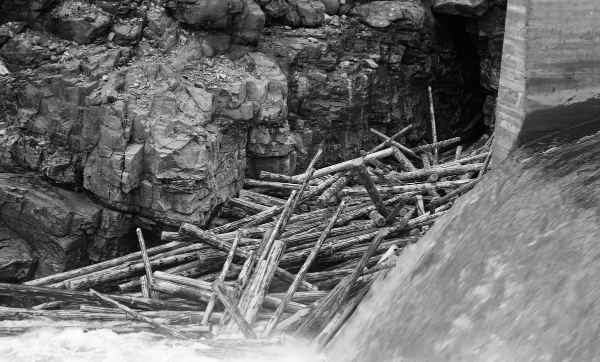 Tømmervase ved Vinstra Bruks dam i Vinstrvassdraget i Nord-Fron kommune i Midt-Gudbrandsdalen. Bildet viser barket tømmer fra de ovenforliggede bygdelaga Kvikne og Skåbu, som hadde filtret seg ihop slik at de stengte det smale elveløpet. Til høyre i forgrunnen ser vi en vannstrøm fra ei betongstøpt renne.