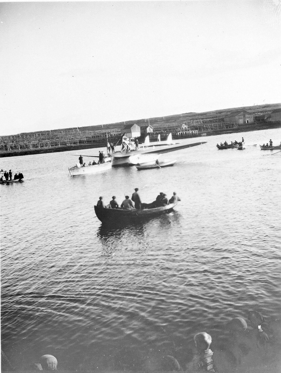 Leting etter luftskipet Italia i 1928. Båter og italiensk sjøfly på vann. Bygninger og fiskehjell på land i bakgrunn. 